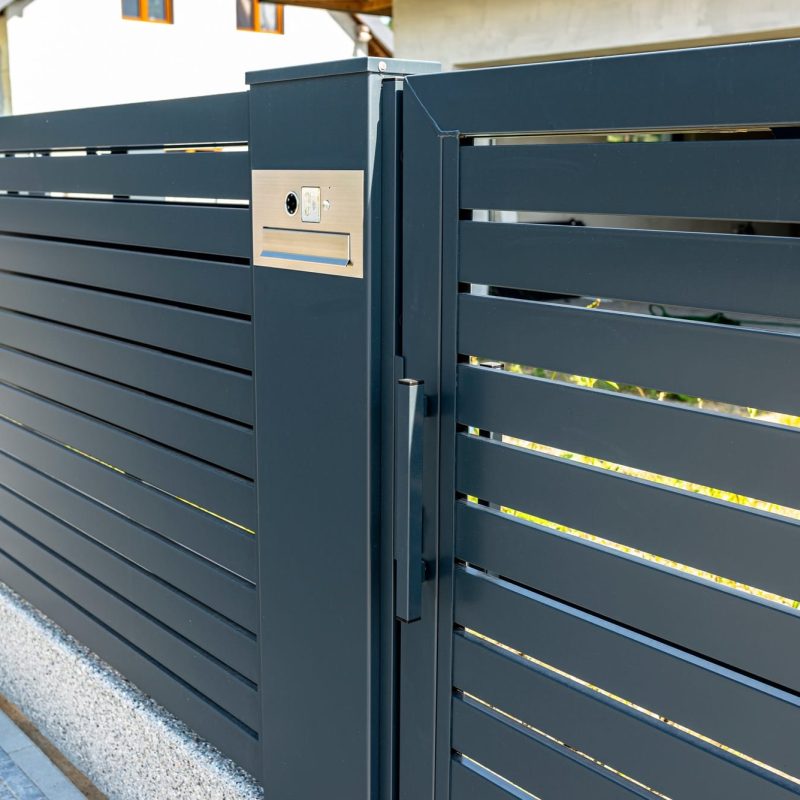 Modern gray metal fence and gate with horizontal slats. Residential security and curb appeal.